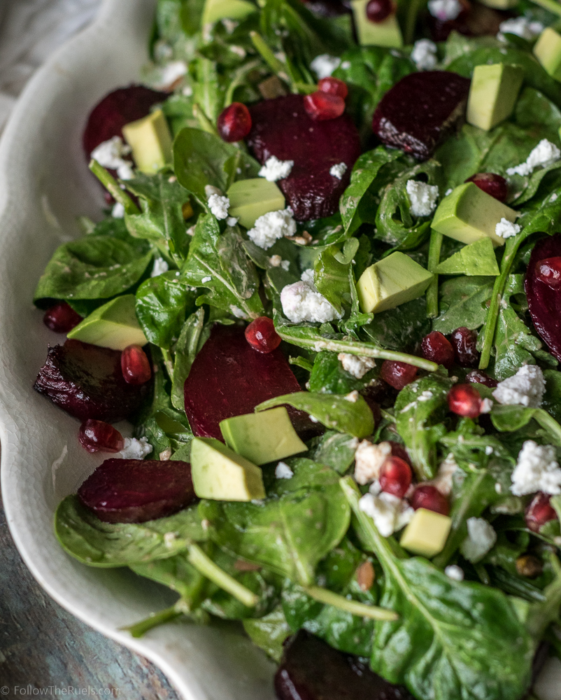 Healthy beet salad topped with avocado, goat cheese, and pomegranate